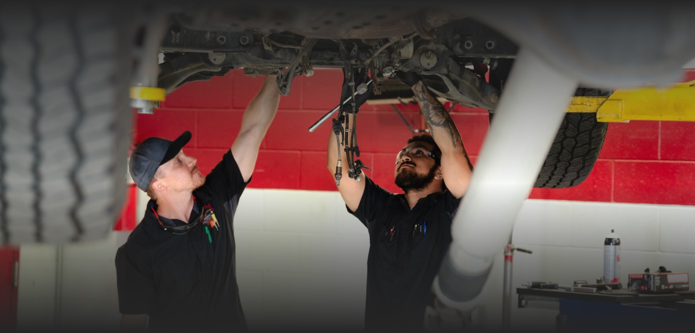 mechanics under a car lifted on forklift