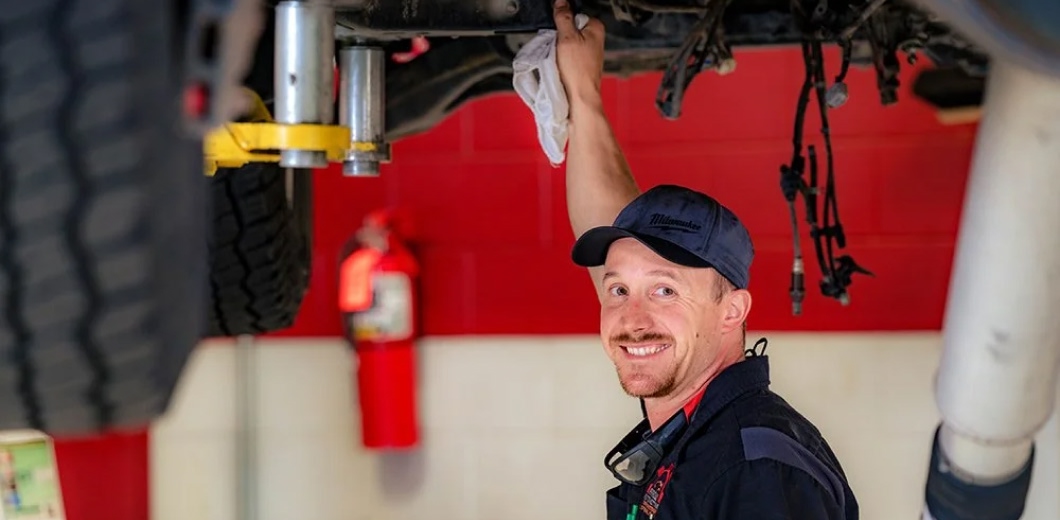 mechanic working on a car, car lifted on a forklift