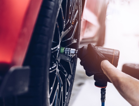 mechanic using hydraulic gun to remove car wheel bolts