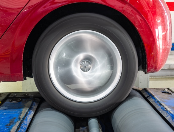 car on dyno machine, with wheels spinning
