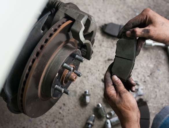 mechanic holding brake pads in his hands, replacing them
