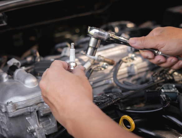 mechanic holding torque wrench and a spark plug in his hands